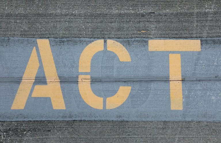 Act Now Schriftzug "Act" auf Asphalt